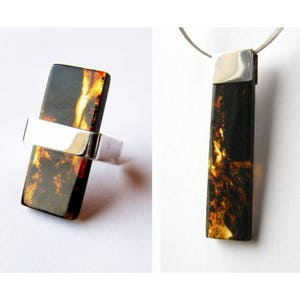 May include: A silver ring and pendant set featuring a rectangular piece of amber. The amber is dark brown with streaks of yellow and orange.