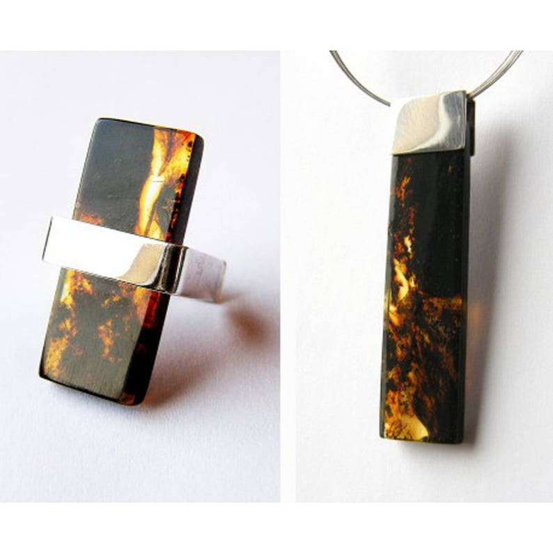 May include: A silver ring and pendant set featuring a rectangular piece of amber. The amber is dark brown with streaks of yellow and orange.