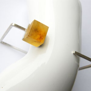 May include: A silver geometric ring with a clear amber cube in the center.