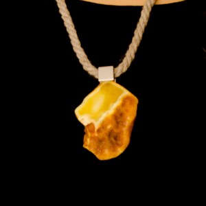 May include: A yellow amber pendant on a rope necklace. The pendant is a natural, irregular shape with a light yellow center and a darker brown outer edge.