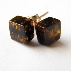 Puede incluir: Un par de pendientes cuadrados de ámbar con motas doradas. Los pendientes están engastados en plata.