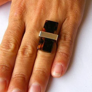 May include: A silver ring with a rectangular brown stone set in the center. The stone has a marbled pattern.