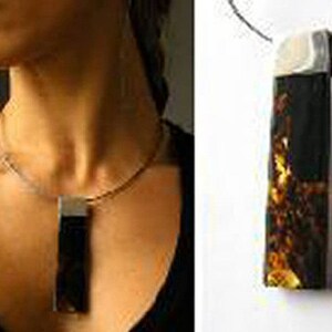 May include: A silver chain necklace with a rectangular pendant featuring a dark amber stone with gold flecks.