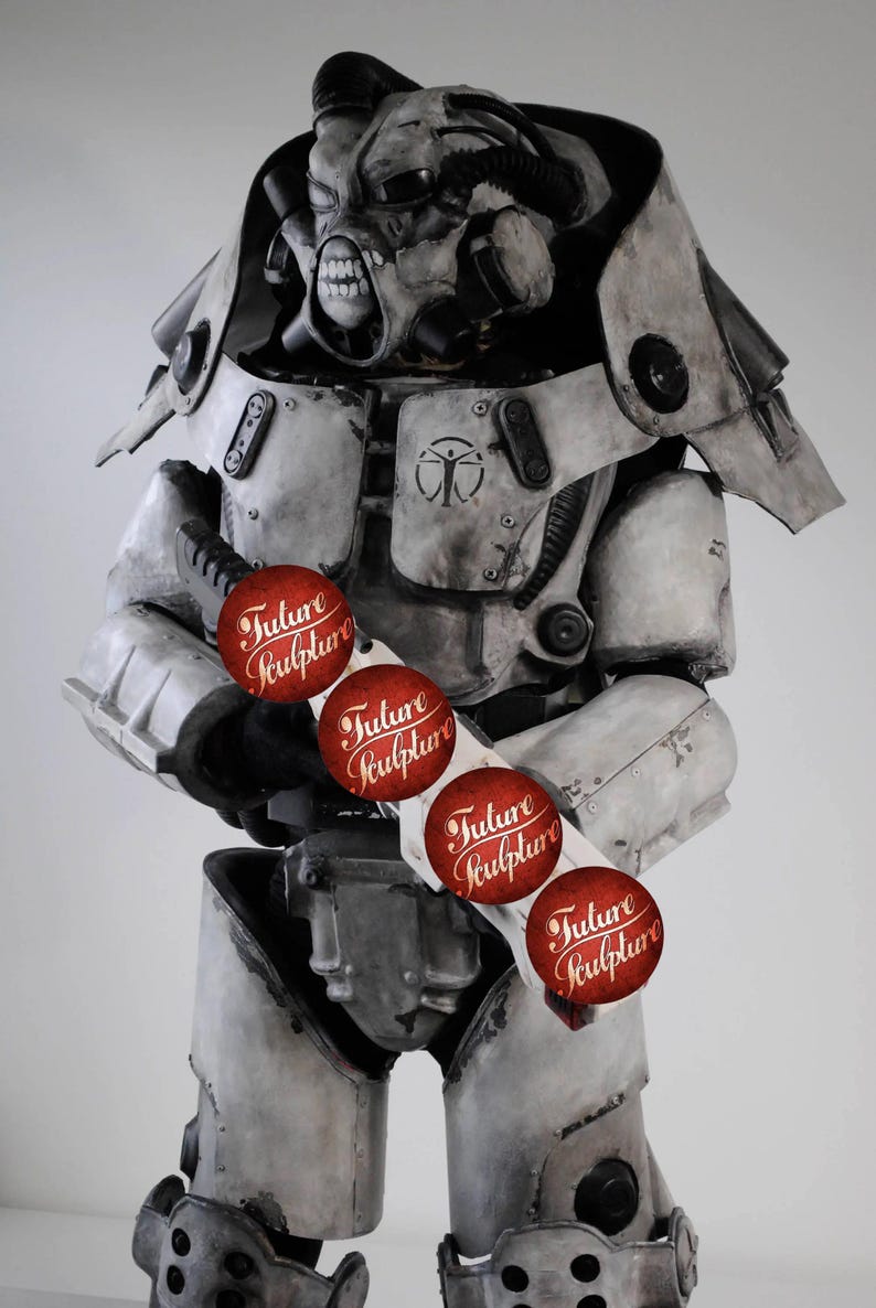 May include: A white and gray robot wearing a helmet with a skull-like face. The robot is holding a weapon with red stickers that say "Future Sculpture" on them.