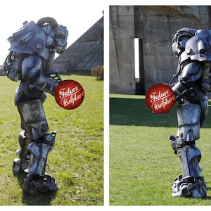 May include: A gray and silver robot costume with a futuristic design. The robot is holding a red sign that says "Future Sculptor".