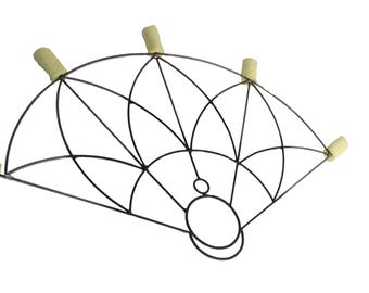 May include: A black metal fire fan with a geometric design, featuring six tan-coloured wicks. The fan has a circular handle and is designed for performance or display. The fan is set against a white background.
