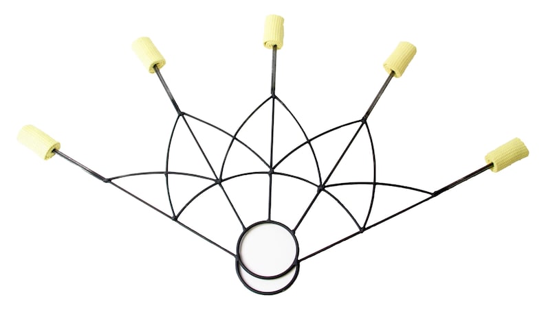 May include: A black metal fire fan with six wicks. The fan has a geometric design with a circular handle. The wicks are cylindrical and yellow. The fan is designed for fire performance.