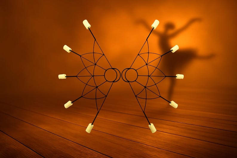May include: Two symmetrical fire poi, each with a black frame and eight white-tipped wicks. The props are set against a warm orange background with a dancer's silhouette, suggesting performance or flow arts.