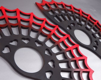 May include: Two black and red wooden fan-shaped wall decor pieces with a spiderweb design and heart cutouts.
