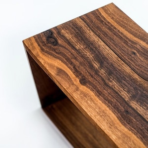May include: A wooden box with a dark brown finish and a natural wood grain pattern. The box is open and empty.
