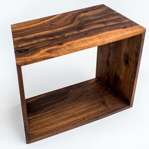 May include: A wooden end table with a square open frame. The table is made of dark brown wood with a natural wood grain.