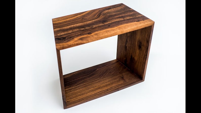 May include: A wooden end table with a square open frame. The table is made of dark brown wood with a natural wood grain.