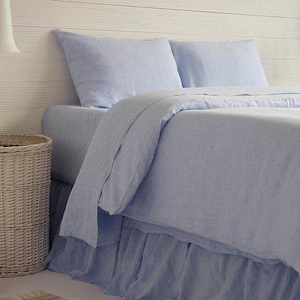 May include: A light blue linen bedding set with a ruffled bed skirt. The bedding is made of a soft, breathable fabric and is perfect for a bedroom.