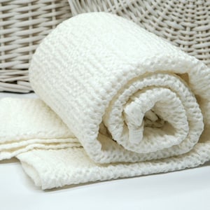 May include: A white waffle weave throw blanket rolled up, with a soft, textured surface.