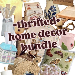 May include: A collection of thrifted home decor items, including a floral-decorated mug, a cat-shaped utensil holder, and a decorative plate. The image also features a small house-shaped tissue box, a bunny figurine, and a pillow with butterfly designs.