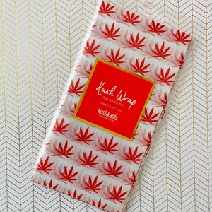 K&ouml;nnte beinhalten: Eine Packung rotes Kush Wrap Seidenpapier mit Punkten und einem roten Etikett mit der Aufschrift "Kush Wrap Red Polka Pot 5 Sheets 15" x 20" kushkards kushkards.com"