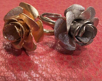 May include: Two rose-shaped rings, one gold and one silver, with a textured finish. The rings are stacked on top of each other.