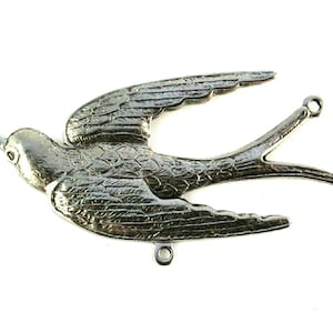 May include: Silver metal swallow bird charm with detailed wings and a textured body. The charm has three loops for attaching to jewelry or other crafts.