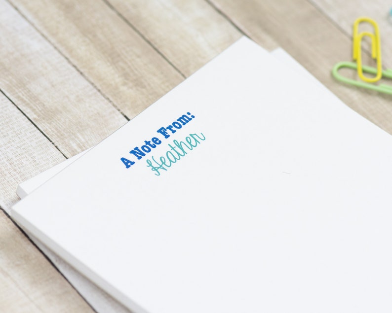 May include: A white notepad with the text "A Note From: Heather" printed in blue and teal.
