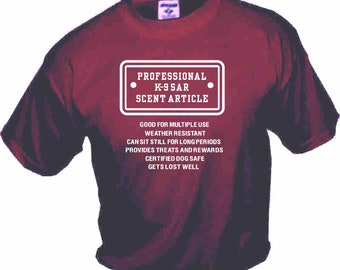 Op de afbeelding: Bordeauxrood T-shirt met witte tekst die "PROFESSIONAL K-9 SAR SCENT ARTICLE" luidt en een lijst met eigenschappen voor een professionele zoek- en reddingshond.