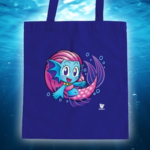 May include: A blue tote bag with a cartoon mermaid with pink hair and a blue tail. The mermaid is smiling and has a gold necklace. The bag has a white background and the text "@corpikun" in the bottom right corner.