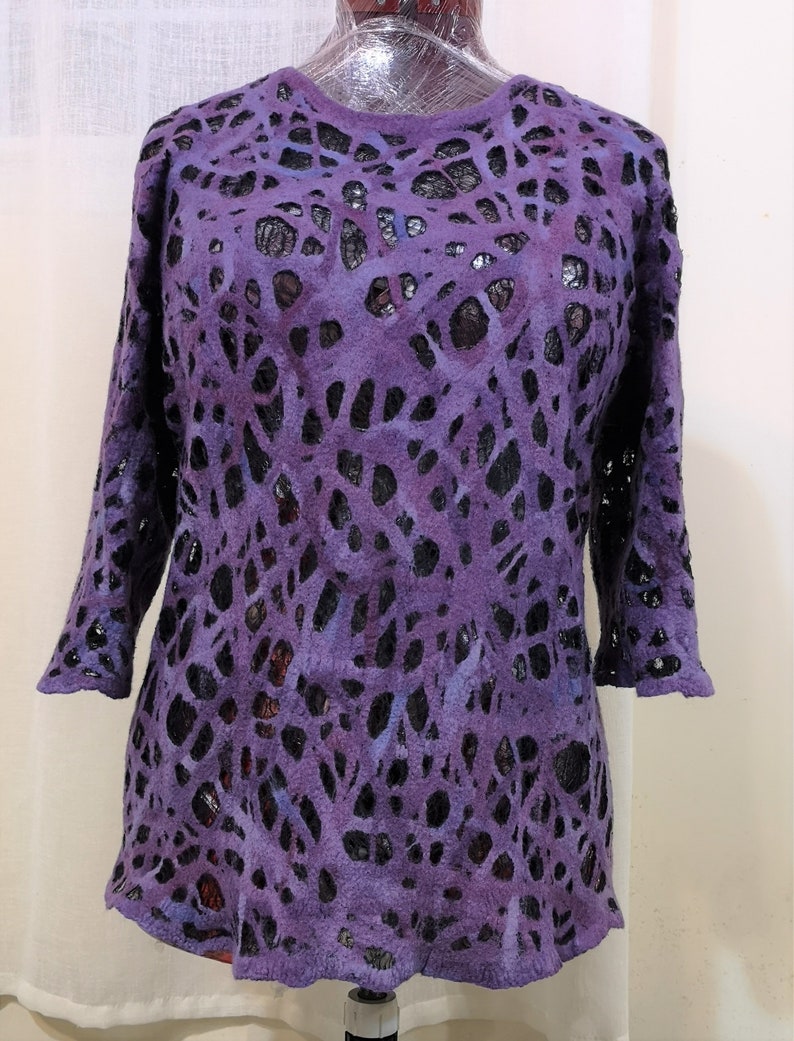 May include: Purple and black patterned sweater with a loose fit and 3/4 sleeves. The sweater has a unique design with cutouts that create a lace-like effect.