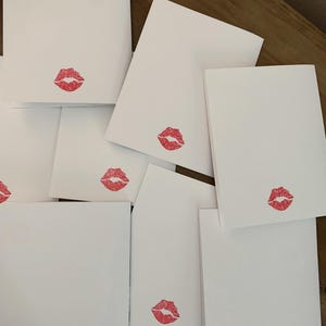 May include: A stack of blank white cards with a red lipstick kiss mark on each card.