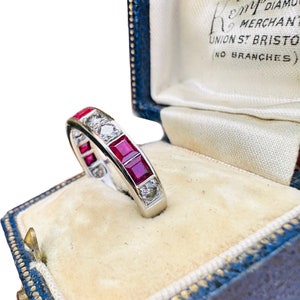 May include: A platinum eternity band ring with alternating red rubies and diamonds. The ring is in a blue velvet ring box with the inscription "K.M. Diamond Merchant Union St. Bristol (No Branches)".
