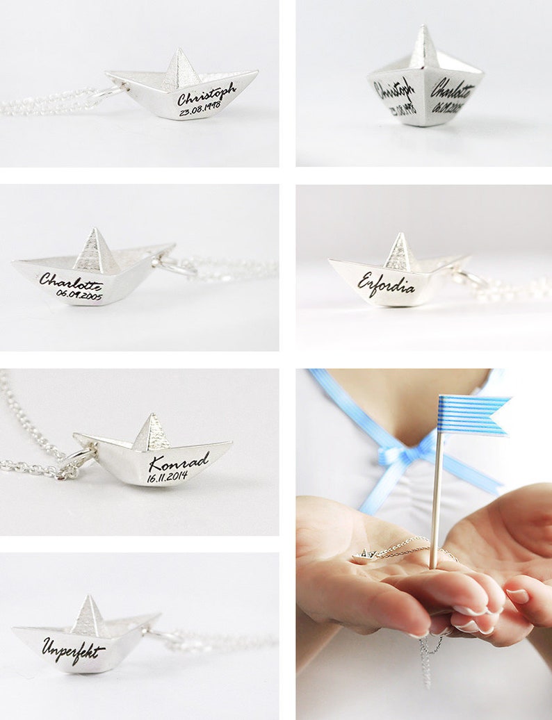 May include: Five silver paper boat necklaces with different names and dates engraved on them. The necklaces are displayed on a white background. One of the necklaces is displayed on a hand with a blue and white striped flag.