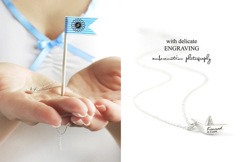 May include: A silver necklace with a small paper boat pendant. The pendant is engraved with the name "Konrad" and the date "16.11.2014".