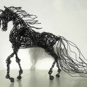 Puede incluir: Una escultura de alambre negro de un caballo con una melena y cola fluidas. El caballo est&aacute; en posici&oacute;n de caminar con la cabeza en alto.