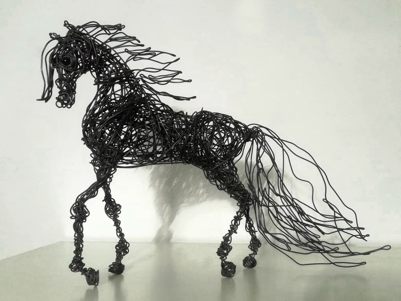 Puede incluir: Una escultura de alambre negro de un caballo con una melena y cola fluidas. El caballo est&aacute; en posici&oacute;n de caminar con la cabeza en alto.