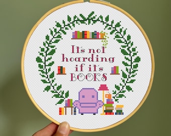 May include: Embroidered hoop art with a green leafy wreath, a pink armchair, and books. The text reads "It's not hoarding if it's BOOKS."