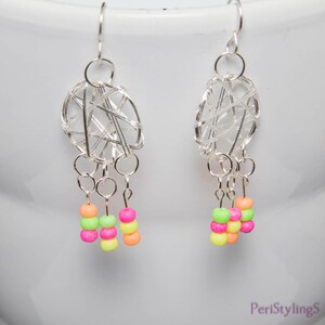 May include: A pair of silver wire earrings with a woven oval design and dangling strands of neon-colored beads. The beads are in shades of pink, green, yellow, and orange. The earrings have a hook closure.