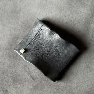 Peut inclure: Une petite pochette en cuir noir avec une fermeture à bouton doré.