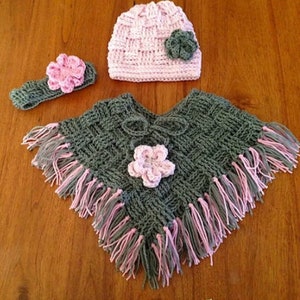 May include: A crocheted set for a baby, including a green and pink poncho with fringe, a pink beanie with a green flower, and a green headband with a pink flower.