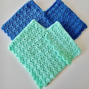 May include: Two crocheted ponchos, one in a light blue color and one in a light green color. Both ponchos have a scalloped edge.