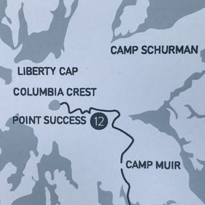 May include: A black and white map with a gray background. The map shows a trail with the text "Point Success 12" and the names of locations: "Liberty Cap", "Columbia Crest", "Camp Schurman", and "Camp Muir".