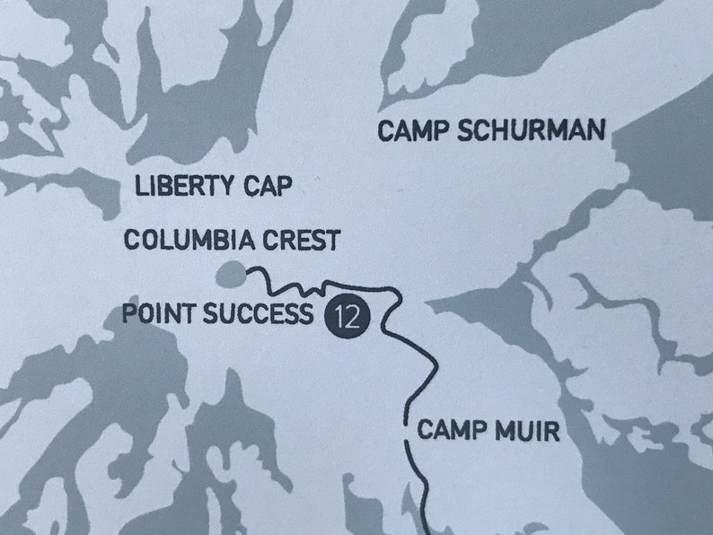 May include: A black and white map with a gray background. The map shows a trail with the text "Point Success 12" and the names of locations: "Liberty Cap", "Columbia Crest", "Camp Schurman", and "Camp Muir".