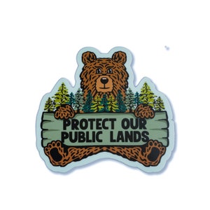 May include: A brown bear with a green forest background holding a sign that says "Protect Our Public Lands".