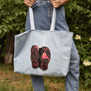 May include: A light blue denim tote bag with two red and black flip-flop patches that say "Rio" on them.