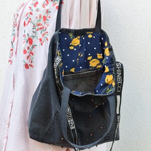 May include: A gray denim tote bag with a floral fabric lining and a black strap with the text "SHINECCI" printed on it. The bag has a pocket on the inside and is decorated with black beads.