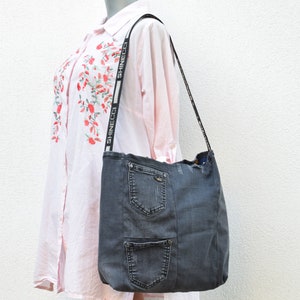 May include: A gray denim tote bag with a long strap featuring the text "SHINECCO" repeated. The bag has multiple pockets and a distressed look.