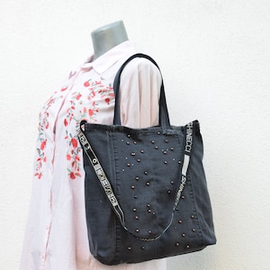 May include: A dark gray denim tote bag with a black strap and silver studs. The strap has the text "Shinecoci" printed on it.