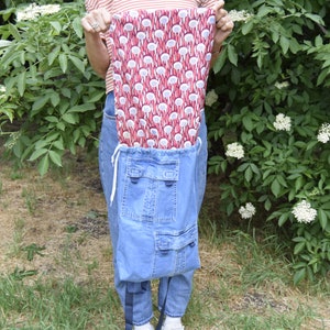 May include: A blue denim backpack with two large pockets and a red and white patterned drawstring bag inside.