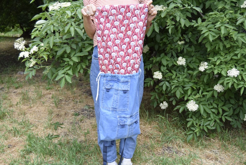 May include: A blue denim backpack with two large pockets and a red and white patterned drawstring bag inside.