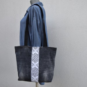 May include: A denim tote bag with a white lace trim. The bag has black straps and a distressed look.