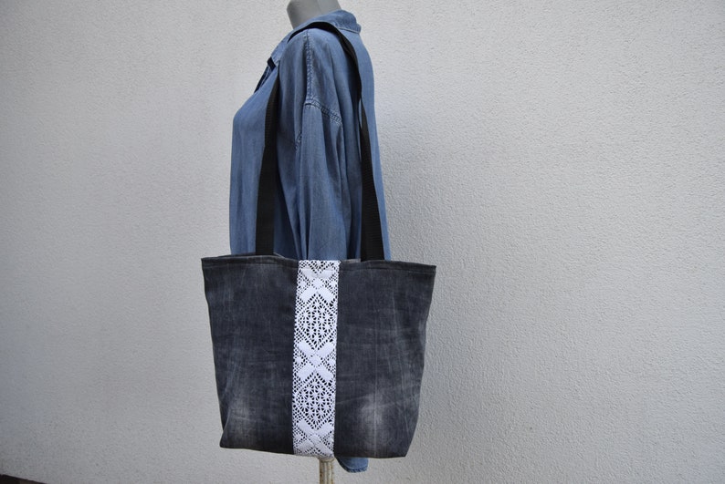 May include: A denim tote bag with a white lace trim. The bag has black straps and a distressed look.