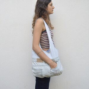May include: A light blue denim tote bag with a white fabric lining and a white lace trim. The bag is worn over the shoulder of a person wearing a striped shirt.