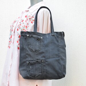 May include: A gray denim tote bag with multiple pockets. The bag has black handles and a zipper closure.